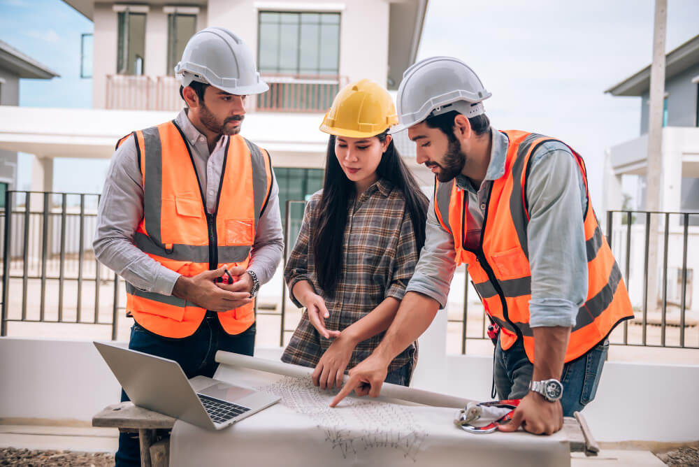 engenheiro-civil-trabalhador-da-construcao-civil-e-arquitetos-usando-capacetes-e-coletes-de-seguranca-estao-trabalhando-juntos-no-canteiro